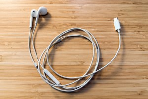 A pair of wired earpods rolled up on a wooden surface.