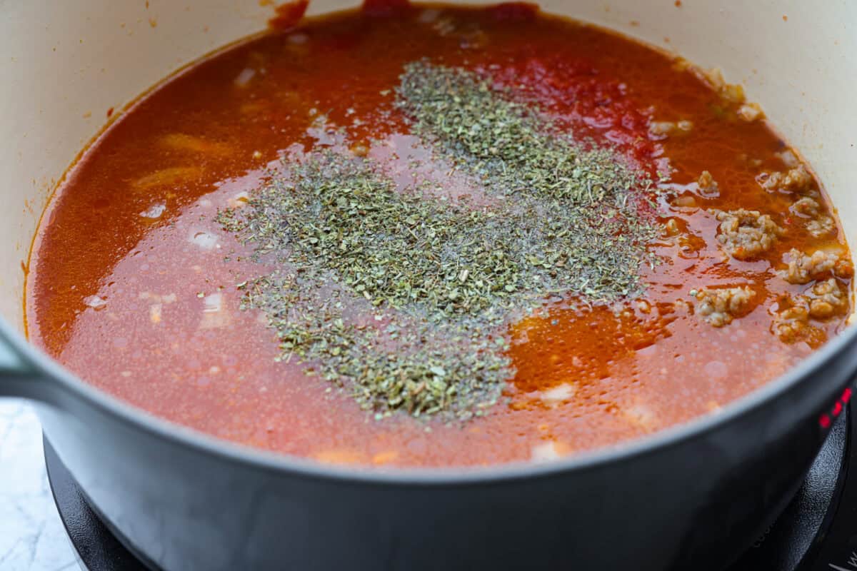 Broth, seasoning, and crushed tomatoes added to the meat mixture.
